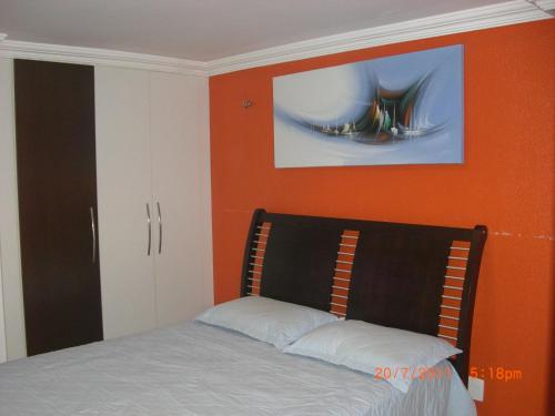 una camera con un letto con una parete arancione di Apartamento na Praia do Futuro a Fortaleza