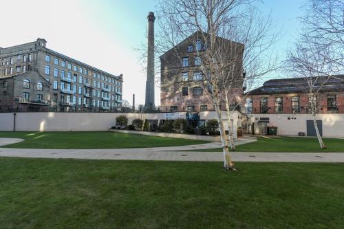 a tree in a park in front of a building at Victoria Mills Apartment Shipley in Shipley