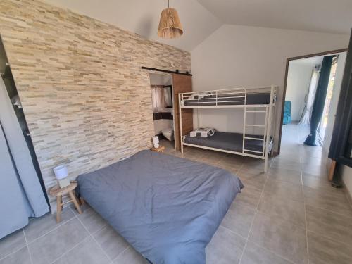 une chambre avec un lit et un mur de briques dans l'établissement Villa climatisée, à Saint-Ambroix