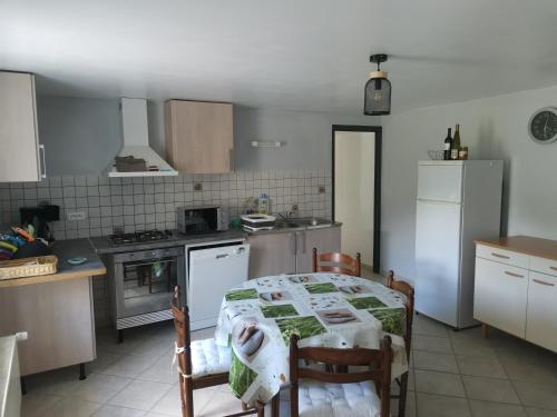 une cuisine avec une table et des chaises et une cuisine avec des appareils blancs dans l'établissement le moulin mallat - 255 rue camille claudel - 43300 mazeyrat d'allier, à Mazeyrat-d'Allier