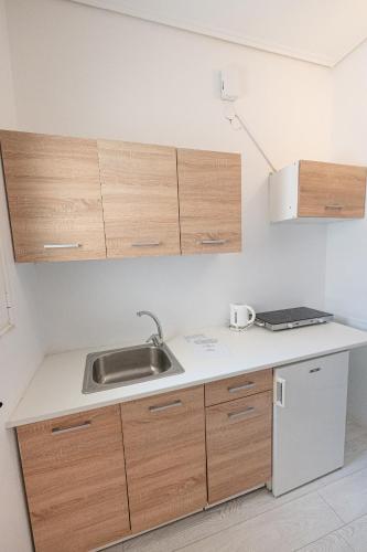 a kitchen with a sink and wooden cabinets at The White Rose Hotel in Poros