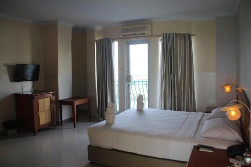 ein Schlafzimmer mit einem großen Bett und einem Fenster in der Unterkunft Hotel Celebes in Manado