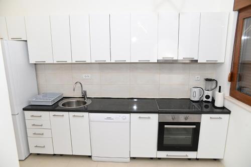 a white kitchen with white cabinets and a sink at Villa Panorama - autumn luxury villa - heated pool and jacuzzi in Ivanica
