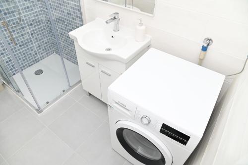 a bathroom with a washing machine and a sink at Villa Panorama - autumn luxury villa - heated pool and jacuzzi in Ivanica