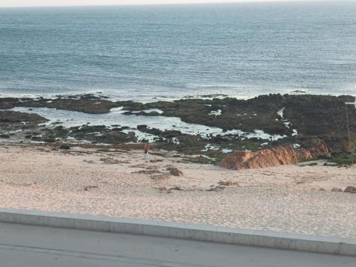 a view of a beach with rocks and the ocean at Cachinnans Hostel & Apartments in Vila do Conde