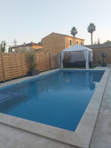 une grande piscine bleue avec un gazebo dans l'établissement Maison avec piscine privée, à Nîmes