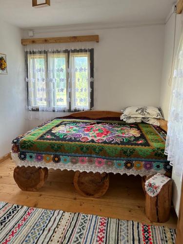 a bedroom with a bed with a colorful blanket on it at Căsuța Bunicilor din Rai in Tulgheş