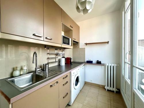 une cuisine avec un évier et une machine à laver dans l'établissement Woody - Parc Salengro - Balcon, à Clichy