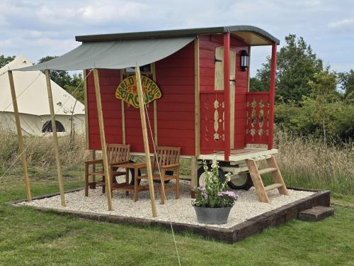 a red tiny house with two chairs and an umbrella at Restored circus wagon in Saltburn-by-the-Sea