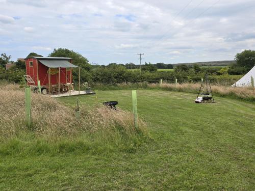a small red house in a field of grass at Restored circus wagon in Saltburn-by-the-Sea