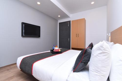 a bedroom with a large bed with a tv on the wall at Townhouse Rudra Inn Near Chhatarpur Metro Station in New Delhi