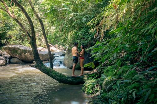 two people standing on a tree branch in a river at Casa Ñi Tayrona in Santa Marta