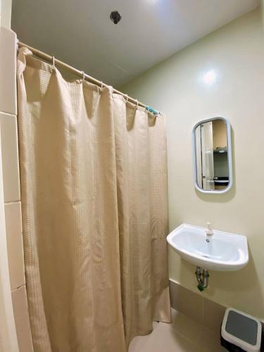 a bathroom with a shower curtain and a sink at CozyNest Rentals at Brenthill Condominium in Baguio