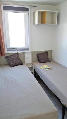 deux lits dans une chambre avec une fenêtre dans l'établissement Mobil Home 10 personnes Camping la Tremblade Emplacement 074, à La Tremblade