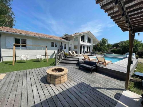 une terrasse en bois avec un foyer devant une maison dans l'établissement Villa de Cazaux, piscine chauffée pétanque billard, à La Teste-de-Buch