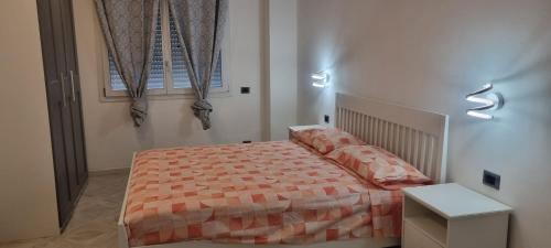 a bedroom with a bed with a orange comforter and a window at Erice IN Appartamenti 1"PLATANI" in Trapani