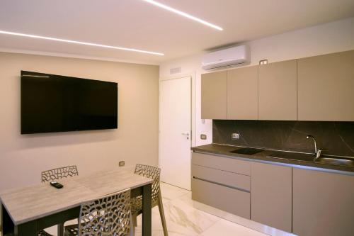 a kitchen with a table and a tv on the wall at Belmà Aparthotel and Rooms in Marina di Camerota
