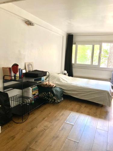 une chambre avec un lit et une fenêtre dans l'établissement Charmant Appartement Proche des Buttes-Chaumont, à Paris
