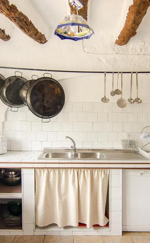 a kitchen with a sink and pots and pans on the wall at Cortijo Alzamigaja in Archidona