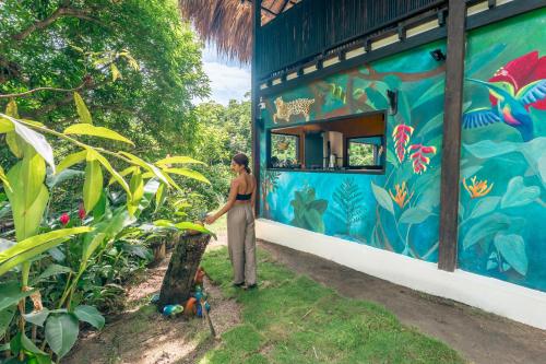 a woman standing in front of a blue building with a mural at Casa Ñi Tayrona in Santa Marta