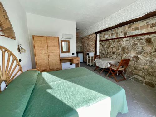 a bedroom with a green bed and a stone wall at Villa Raffaela - Appartamenti Lacco Ameno in Lacco Ameno