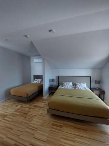 two beds in a large room with wooden floors at VerMar in Torreira