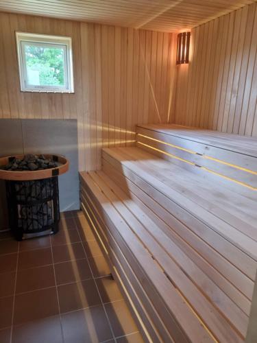 a sauna with a tub and a table in it at Namelis su sauna ir jakuzi in Virbališkiai