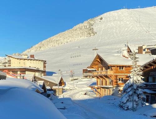 a ski lodge in the snow with a mountain in the background at Homency - Chalet Jepima II in L'Alpe-d'Huez