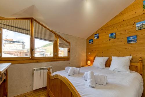 a bedroom with a large bed with wooden walls at Homency - Chalet Jepima II in L'Alpe-d'Huez