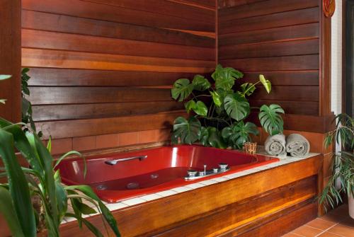 a red bath tub in a wooden wall with plants at Abbey's Lantern Hill Inn in Ledyard Center