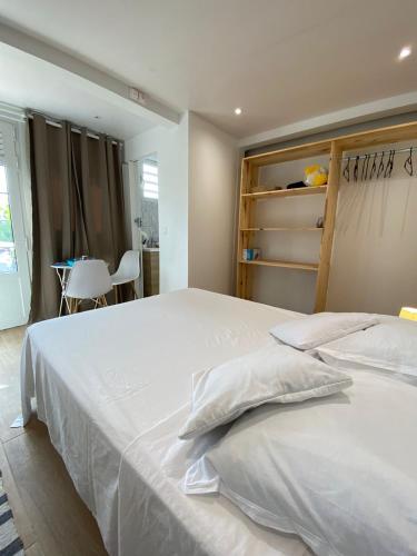 Un dormitorio con una gran cama blanca y una mesa. en Studio coco 2 personnes, en Le Lamentin