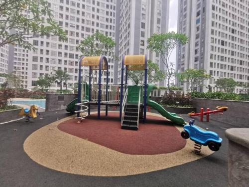 einen Spielplatz mit Rutsche in einem Park mit hohen Gebäuden in der Unterkunft M Town Residence Apartment Serpong 1 Bedroom in Pumpangsineng