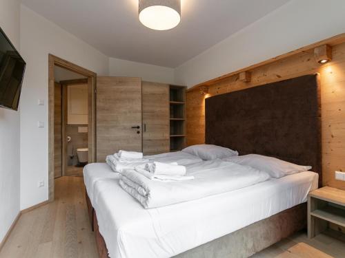 a bedroom with a large white bed with a wooden wall at Apart33 Top 2-3B in Haus im Ennstal