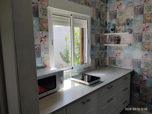 cocina con microondas y ventana en Cabaña EL SALTO DEL DUENDE, en Carrión de los Céspedes