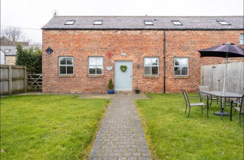 a brick house with a table and an umbrella at Bogma Cottages in Durham
