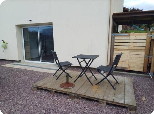 a picnic table and two chairs in front of a building at Le val in Thaon