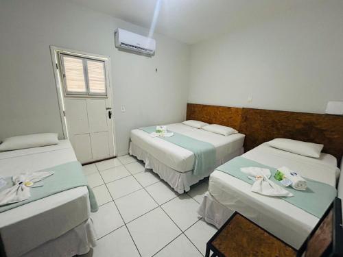 a hotel room with two beds and a window at Mansomar in Jericoacoara