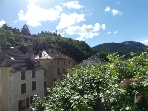 a group of buildings and trees with mountains in the background at Gîte de séjour et d'étape l'Escampette in Saint-Jean-du-Bruel
