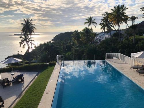 a large swimming pool with a view of the ocean at Paradise Retreat Peace Relaxation in Santa Bárbara de Samaná