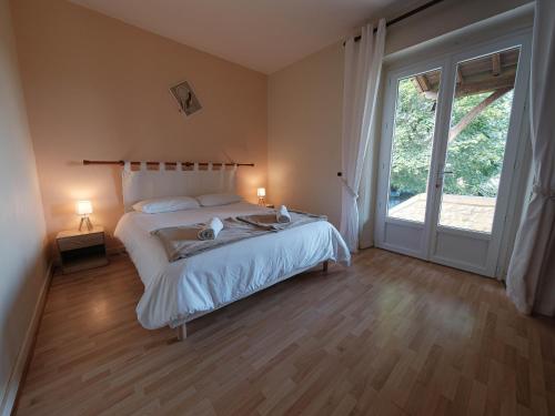 une chambre avec un lit et une grande fenêtre dans l'établissement Grande maison en Périgord à 10 mn de Sarlat, à Marquay