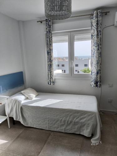 a bedroom with a bed and a window at Casa adosada Rompeolas-Atlanterra in Zahara de los Atunes