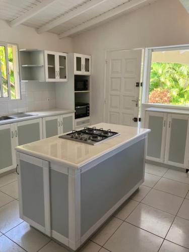 a white kitchen with a stove top island in it at Villa Bleu Horizon in Bouillante