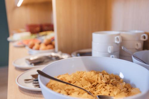 a bowl of cereal on a table with plates of food at Mondragon Hotela in Arrasate - Mondragon