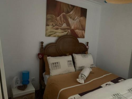 a bedroom with a bed with a painting on the wall at Casinha in Quintela