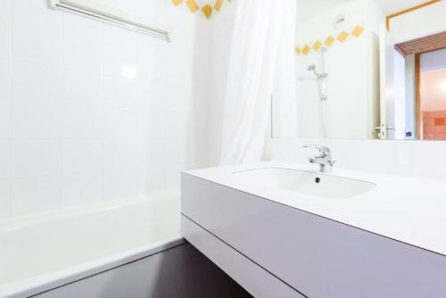 une salle de bain blanche avec un lavabo et un miroir dans l'établissement Quartier Crève Cœur - maeva Home - 2 Pièces 5 Personnes Confort MAE-3793, à Valmorel