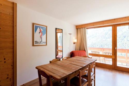 une salle à manger avec une table en bois et une fenêtre dans l'établissement Résidence Les Sentiers du Tueda - maeva Home - 3 Pièces 8 Personnes - Sélection MAE-4084, à Les Allues