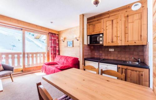 Il comprend une cuisine et un salon avec un canapé rouge et une table. dans l'établissement Résidence Les Sentiers du Tueda - maeva Home - 2 Pièces 4 Personnes Confort MAE-4101, à Les Allues