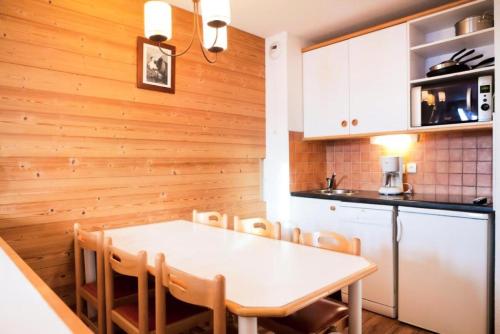 une cuisine avec une table et des chaises dans une pièce dans l'établissement Résidence Les Constellations - maeva Home - 2 Pièces 7 Personnes Sélection MAE-4157, à La Plagne Tarentaise