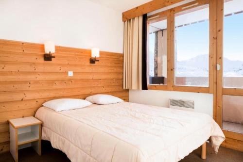 une chambre avec un lit et une grande fenêtre dans l'établissement Résidence Les Constellations - maeva Home - 2 Pièces 7 Personnes Sélection MAE-4157, à La Plagne Tarentaise