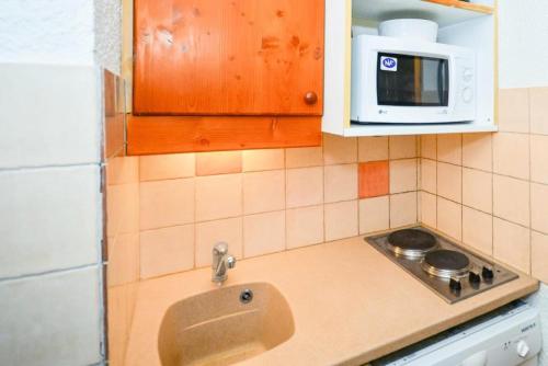 une cuisine avec un évier et un micro-ondes dans l'établissement Quartier Crève Cœur - maeva Home - Studio 4 Personnes Confort MAE-4153, à Valmorel